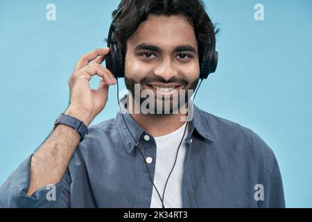 Uomo arabo sorridente che indossa cuffie per ascoltare musica o podcast. Primo piano Foto Stock