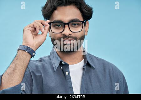 Giovane arabo fiducioso che indossa occhiali isolati su sfondo blu. Foto Stock