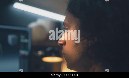 Primo piano di un uomo concentrato che guarda lo schermo del computer mentre lavora in remoto su un progetto di modellazione 3D freelance da casa Foto Stock