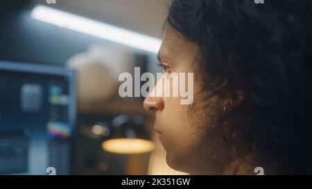 Primo piano di un uomo concentrato che guarda lo schermo del computer mentre lavora in remoto su un progetto di modellazione 3D freelance da casa Foto Stock