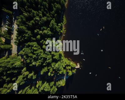 Vista aerea. Un grande fiume blu scuro e una fitta foresta di conifere sulla riva. Crepuscolo. Natura pittoresca, scene calme. Ambiente ecologico, Foto Stock