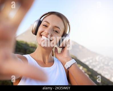 I social media, l'influencer e il ritratto di una donna ascoltano musica e creano contenuti online di viste panoramiche sulle montagne. Fitness, viaggi e blog con un Foto Stock