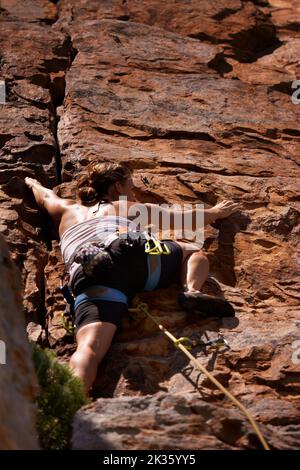 Scalando la faccia della roccia come un pro. Un arrampicatore della roccia femminile che fa una salita del cavo. Foto Stock