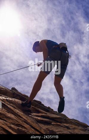 Le semplici gioie dell'arrampicata su roccia. Una giovane ragazza scalatrice di roccia che scende giù per una montagna. Foto Stock