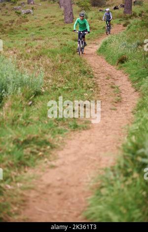 Percorrere il sentiero meno percorso. Due giovani ciclisti che si divertono lungo un sentiero. Foto Stock