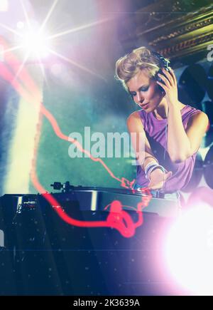 Ascoltare i propri battiti. Una giovane femmina dj che ascolta alcuni mix sulle sue cuffie. Foto Stock