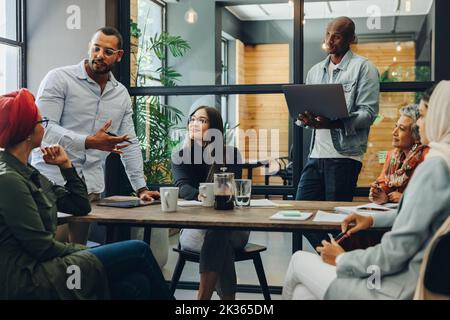 Professionisti aziendali creativi che hanno una discussione di gruppo durante una riunione in un ufficio moderno. Team di imprenditori multiculturali che condividono idee in un Foto Stock
