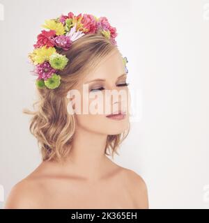 Le paludi sono state incoronate regina della primavera. Una giovane donna che si posa con gli occhi chiusi e fiori nei capelli. Foto Stock