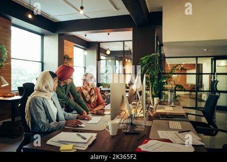 Allegre donne d'affari che lavorano in team in un moderno ufficio di co-working. Gruppo di donne d'affari multiculturali sorridendo allegro mentre hanno una discussione Foto Stock