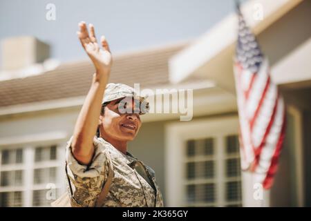 Soldato patriottico che sorride e agita la mano con orgoglio mentre si trova fuori casa. Servizio americano tornando a casa dopo averla servita Foto Stock