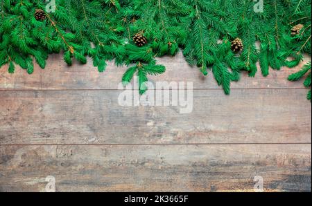 Cornice di Natale con rami di abete su sfondo in legno. Vista dall'alto sfondo natalizio con spazio per i saluti. decorazione natalizia su vecchio bac in legno Foto Stock