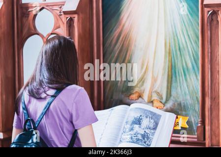 La ragazza prega nella chiesa. Chiesa parrocchiale. La fede cristiana. Lettura davanti all'icona. Tempo di preghiera. Foto Stock