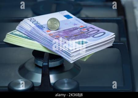 Il rublo russo si trova sulle banconote in euro, vicino a una stufa a gas illuminata a casa. Foto Stock