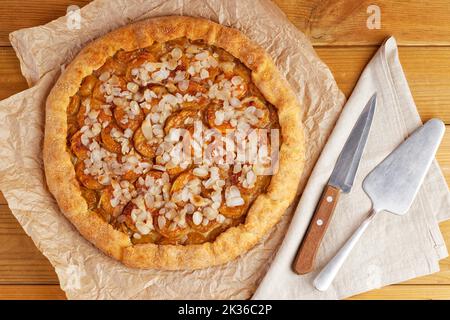 Torta fatta in casa con prugne e petali di mandorle su carta pergamena. Vista dall'alto. Foto Stock