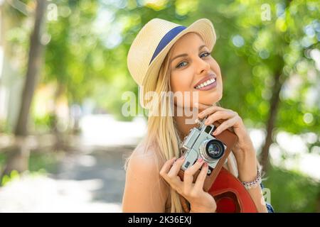 Primo piano ritratto di una giovane donna felice con una fotocamera retro. Sorrideva e guardava la macchina fotografica. Foto Stock