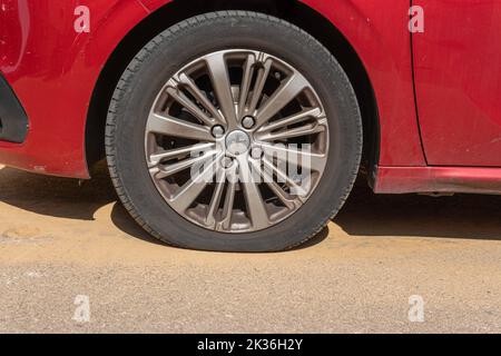 Felanitx, Spagna; settembre 18 2022: Pneumatico forato di una Peugeot 208 rossa, con la sua ruota di scorta pronta per la sostituzione Foto Stock