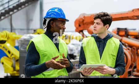 Ingegneri multirazziali che lavorano in una fabbrica robotica - concetto di industria tecnologica Foto Stock