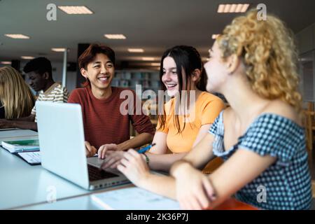 Giovani multirazziali che studiano insieme all'interno della biblioteca universitaria - concetto di educazione scolastica Foto Stock