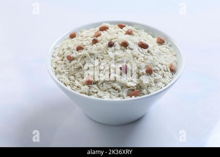 Riso crudo appiattito o scaglie di riso spesso o sottili per spuntini Namkeen Chivda o Alo POHA per colazione indiana, servito in una ciotola. Foto Stock