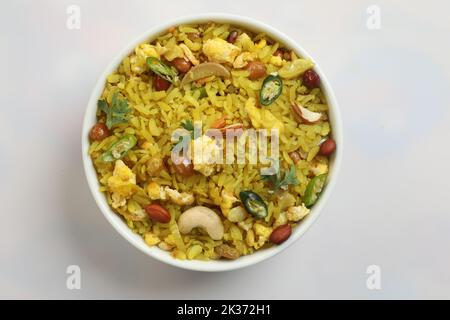 piatto indiano della colazione poha.Indian prima colazione POHA sormontato con arachidi, semi di melograno, freddo verde tagliato, cipolla, lime, foglie di coriandolo e curry Foto Stock