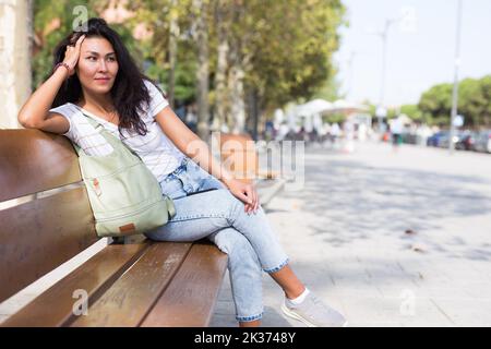 Donna seduta su panca in parco Foto Stock