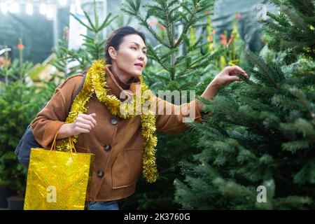 Cliente donna che acquista l'albero di abete al mercato di Natale Foto Stock