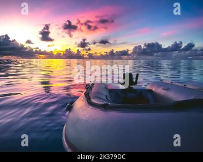 Gommone contro il tramonto tropicale. Il cielo arancione blu rosa brillante si riflette nell'acqua dell'oceano. Incredibile paesaggio estivo naturale. Viaggi, turismo, vacanze Foto Stock