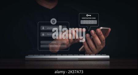Autenticazione in due fasi o concetto 2FA. 2023 Codice di verifica e icona della chiave sullo schermo dello smartphone con tastiera del computer per la pagina convalida password, Foto Stock