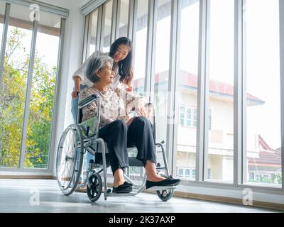 Donna anziana asiatica felice, madre o nonni su sedia a rotelle che si prendono cura da caregiver, sorridendo giovane donna, figlia o nipote che sostiene a h Foto Stock