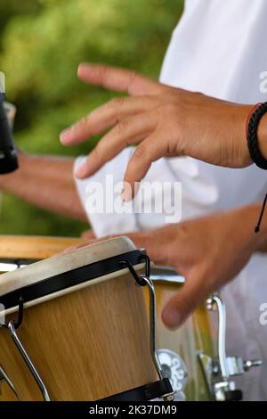 Mani di Un musicista della Salsa Band con Motion Blur suonando i Bongos, Christchurch UK Foto Stock