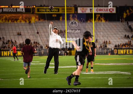 L'allenatore capo provvisorio dello stato dell'Arizona Shaun Aguano gioca a catturare i giovani tifosi prima che la sua squadra prenda il campo per scaldarsi prima di un calciatore dell'università dell'NCAA Foto Stock