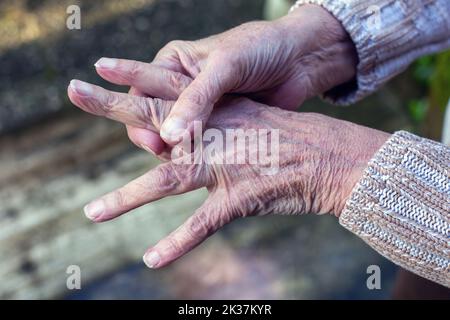 primo piano di una vecchia donna che le sfrega le mani Foto Stock
