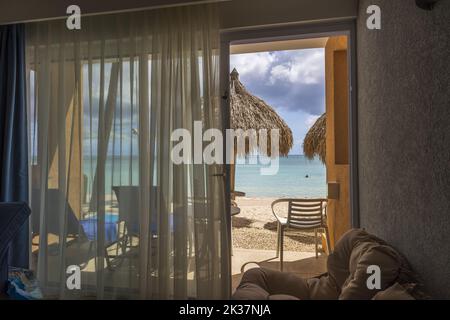 Splendida vista sull'oceano e nuvole puffy sul cielo blu dalla porta di vetro aperta della camera d'albergo. Foto Stock