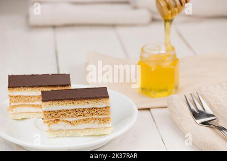 Torta al miele con condimento al cioccolato e panna bianca al burro. Dolce di nozze fatto in casa dessert. Servita su tavolo di legno bianco. Foto Stock