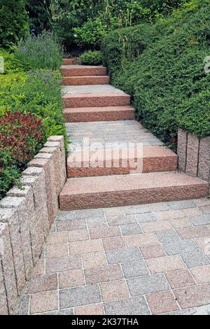 Cortile anteriore ordinato e ordinato con gradini a blocco solido, ghiaia decorativa e piantatura Foto Stock