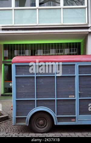 Un'immagine verticale di un furgone di legno blu parcheggiato sulle strade di fronte agli edifici Foto Stock