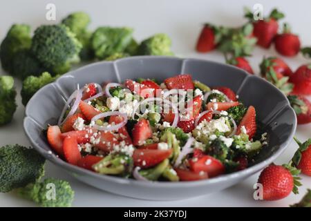 Broccoli con feta e fettine di fragole fresche. I fiori di broccoli saltati sono cosparsi di feta grattugiata e fragole fresche Foto Stock