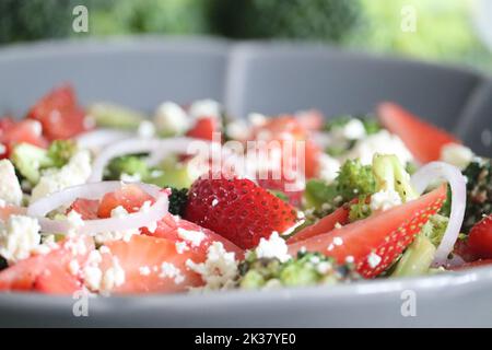 Broccoli con feta e fettine di fragole fresche. I fiori di broccoli saltati sono cosparsi di feta grattugiata e fragole fresche Foto Stock