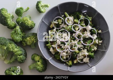 Broccoli con feta e anelli di cipolla. I fiori di broccoli saltati sono cosparsi di feta grattugiata e anelli di cipolla. Piatto sano a s Foto Stock