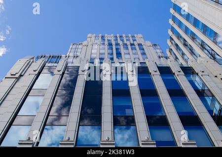 Mosca, Russia, 2020 giugno: Il cielo blu con le nuvole si riflette nel vetro delle finestre identiche del moderno edificio degli uffici. Foto Stock