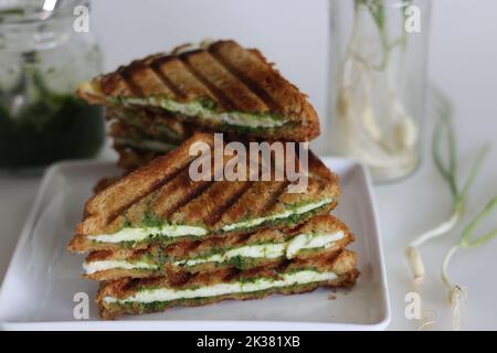 Sandwich con chutney di formaggio. Panini alla griglia con fettine di ricotta e condimenti all'aglio verde. Sandwich con chutney di formaggio. Ripresa su sfondo bianco Foto Stock