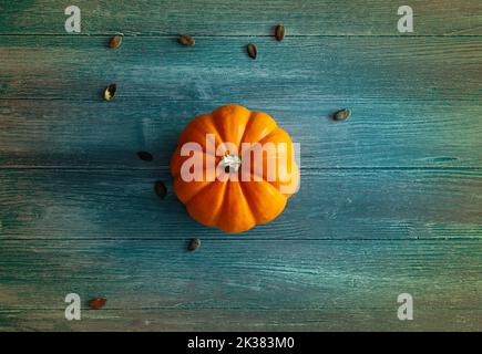 Zucca arancione su sfondo di legno blu e colorato, ideale come sfondo per Halloween o tema autunnale, zucca arancione isolato Foto Stock