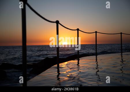 Piscina accanto all'oceano nelle calde tonalità dell'alba a Sydney, nuovo Galles del Sud, Australia Foto Stock