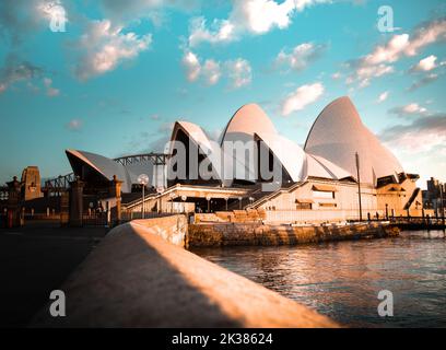 La famosa Sydney Opera House nella calda luce dell'alba con nuvole bianche sul cielo a Sydney, nuovo Galles del Sud, Australia Foto Stock