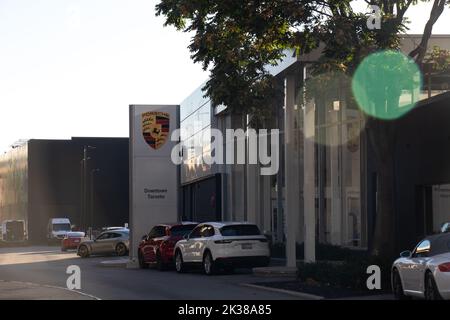 La luce del sole del mattino splende su un concessionario Porsche nel centro di Toronto; le nuove automobili Porsche sono viste fuori di fronte al concessionario automobilistico tedesco. Foto Stock