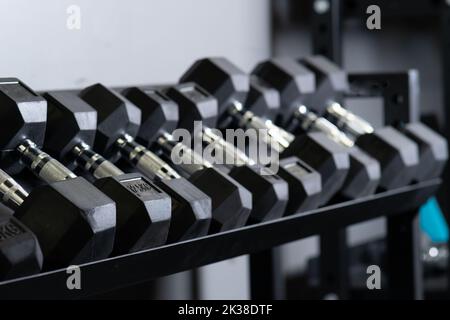 Dumbbell blurry casa palestra parete set di stoccaggio rig sport, concept accessori ingranaggio in primo piano e uomo sano, muscolare in forma. Sollevamento , Foto Stock