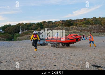 Horton Beach Gower Wales UK RNLI, imbarcazione di salvataggio costiera di ritorno alla stazione di bagnamento dopo l'esercizio con l'aiuto di un veicolo di recupero della spiaggia e dell'equipaggio sulla spiaggia Foto Stock