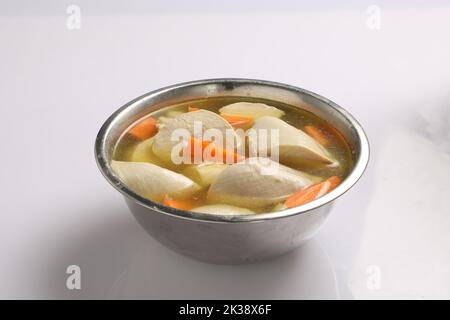 Brodo di pollo trasparente con pezzi di sotto l'acqua corrente. Sapone di pollo con molte verdure e acqua corrente nel processo di preparazione in una pentola Foto Stock