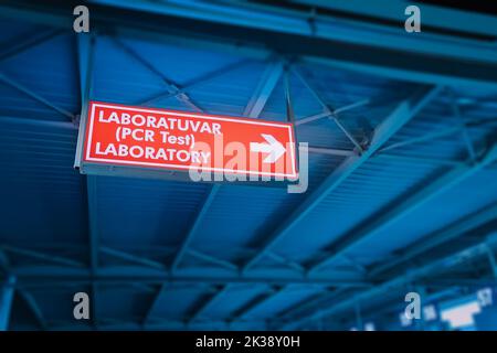 Cartello con indicazioni per il laboratorio di test PCR all'aeroporto turco. Pandemia e infezione da coronavirus Foto Stock