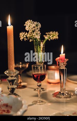 tavolo da sera con candele, cocktail, vino, fiori Foto Stock